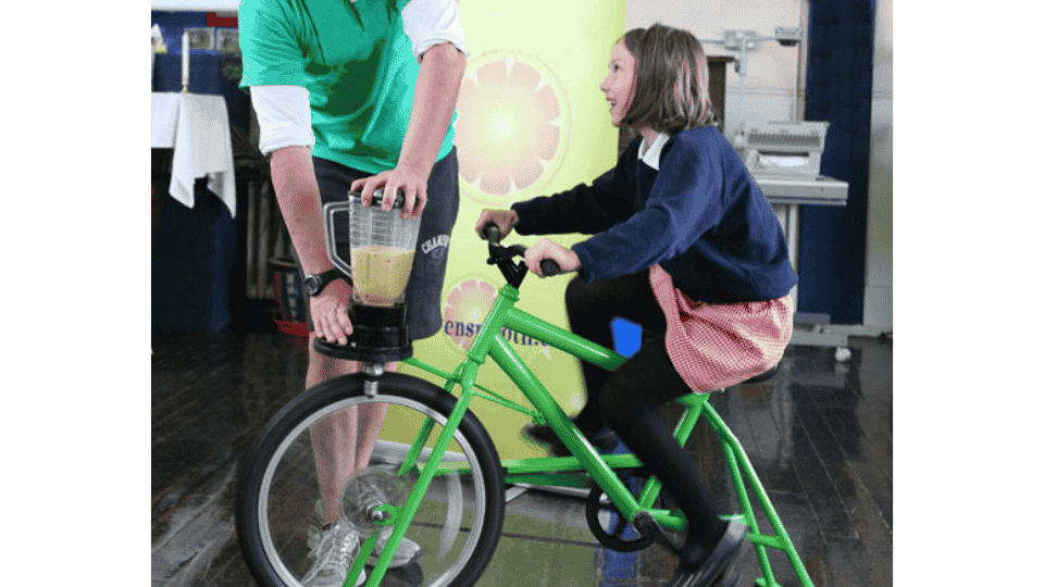 petite fille souriante faisant un smoothie grace a un velo vert
